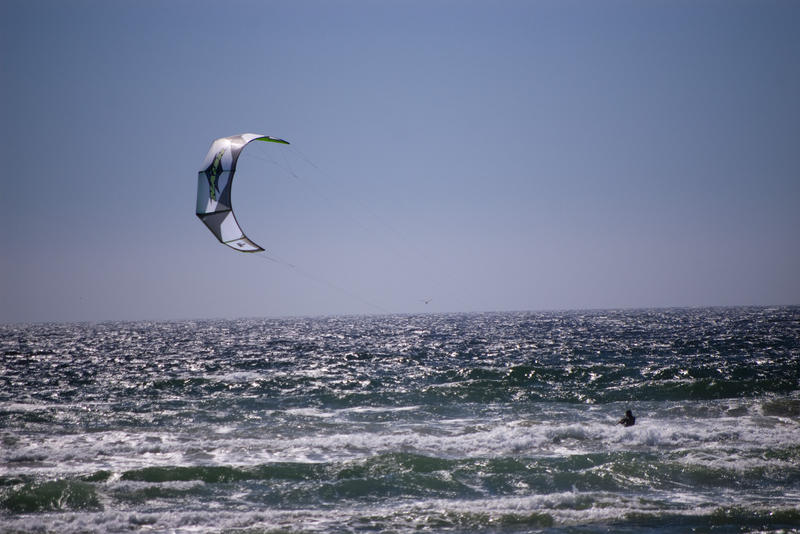 a kitesurfer skirting along the water