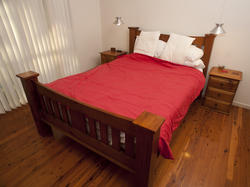 8938   Classic wooden bed with a red bedspread