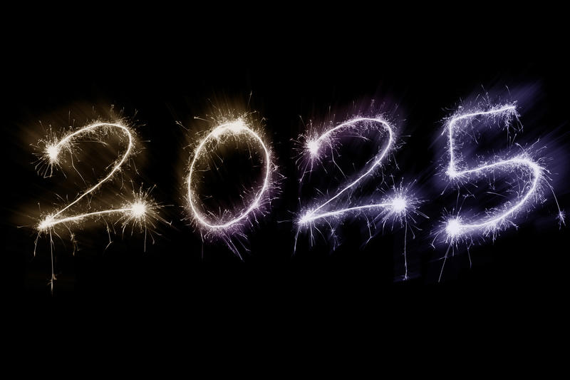 Zooming numbers for New Year 2025 bursting out from a black background shown in bright sparks