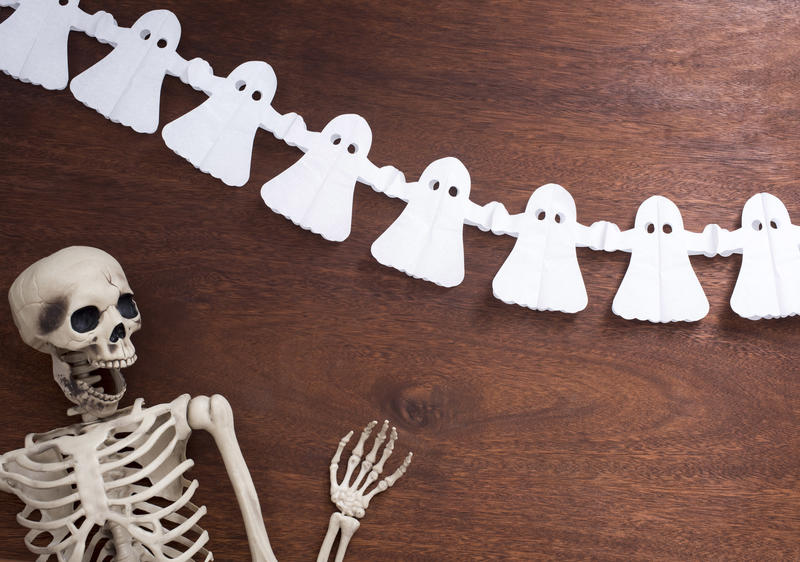 halloween image featuring a jolly looking skeleton and some ghost paper decorations
