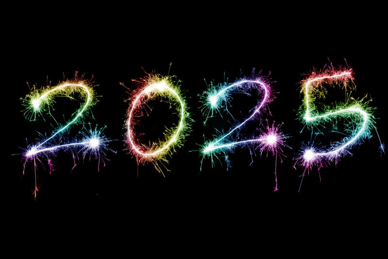 rainbow coloured sparkling fireworks as happy new year holiday 2025 over black background