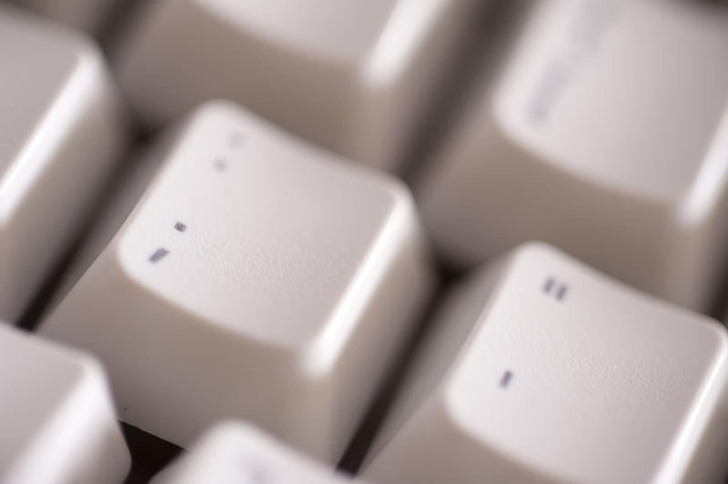a macro image of a computer keyboard with the focus on the semi-colon punctuation key